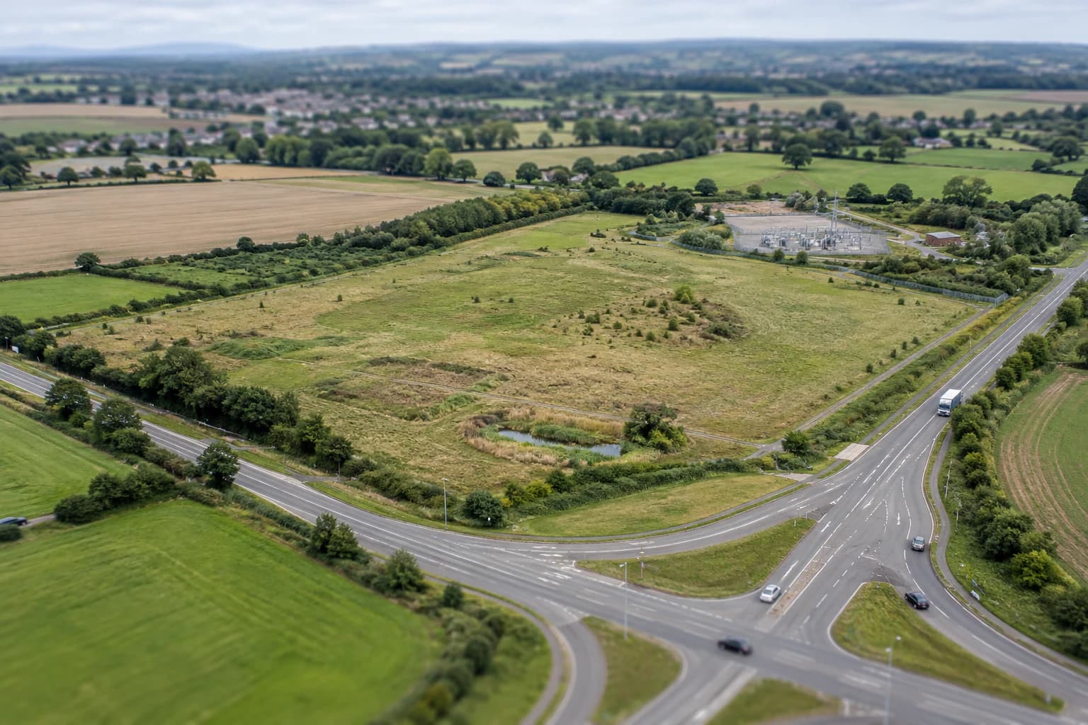 An undeveloped site shown within its roads, infrastructure, and surrounding land context